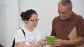 Ein Mann und eine Frau lesen in einem grünen Flyer, den sie in den Händen halten.